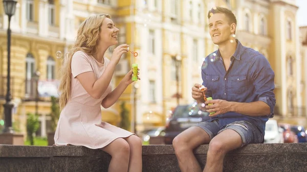 Beautiful couple blowing bubbles and having fun on sunny summer day, romance — Stock Photo, Image