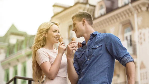 Hombre y mujer enamorados comiendo helado y mirándose, juguetones — Foto de Stock