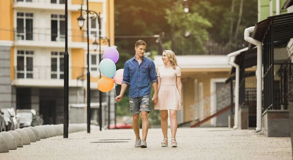 Masculino com balões e fêmea passeando rua abaixo e falando, encontro romântico — Fotografia de Stock