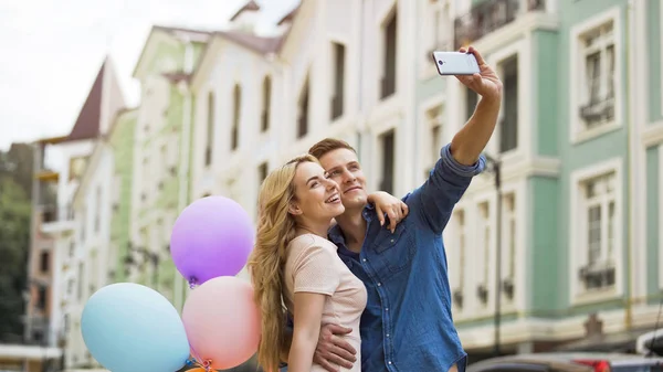 Jovem do sexo feminino e masculino apaixonado abraçando e tirando selfie, memórias românticas — Fotografia de Stock