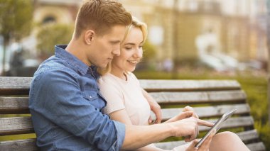 Kız ve banktaoturuyor, erkek arkadaşı gitmek için yer seçimi tablet, kullanma