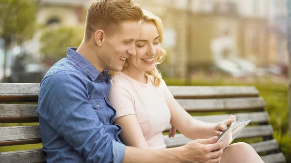 Lächelndes verliebtes Paar betrachtet Fotos aus dem Urlaub per Tablet und Handy-App — Stockfoto