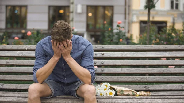 Upprörd ung man sitter på bänken ensam, stängning ansikte med händerna, uppbrott — Stockfoto