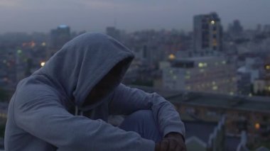 Şaşkın ve hayatta kayıp cityscape, dikkatli bir şekilde bakarak genç erkek suçlu