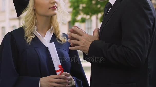 Professor dá instruções de vida para estudante de pós-graduação do sexo feminino em vestido acadêmico — Vídeo de Stock