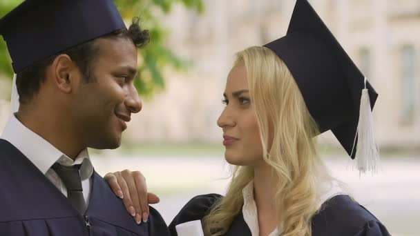 Blond meisje band met haar biracial klasgenoot voor graduatie ceremonie aanpassen — Stockvideo