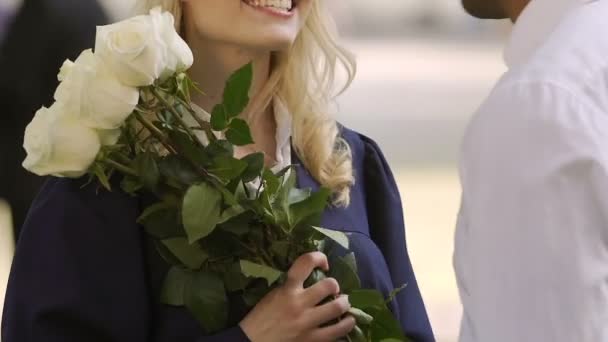 Cara parabenizando seu amado estudante do sexo feminino presenteando seu buquê chique de rosas — Vídeo de Stock