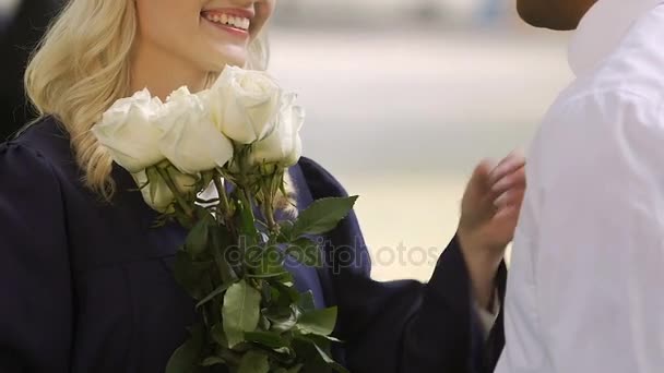 Hombre felicitando novia en la ceremonia de graduación universitaria con flores — Vídeos de Stock