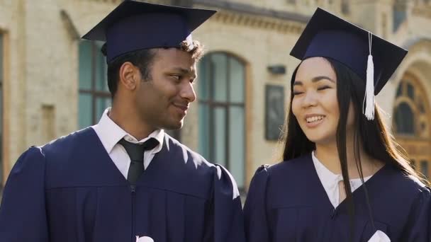 Estudiantes de intercambio multirracial celebrando la graduación, posando con diplomas — Vídeo de stock