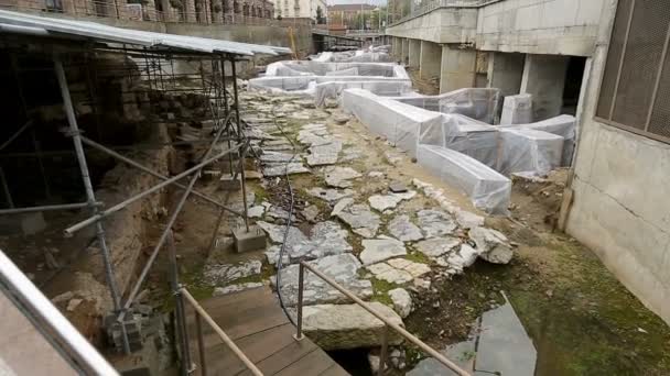 Ruínas antigas escavadas no meio da rua cercadas por edifícios monumentais — Vídeo de Stock