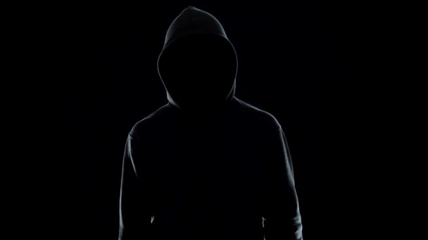 Неузнаваемый мужчина в капюшоне, держит шприц на черном фоне, концепция наркотиков — стоковое видео