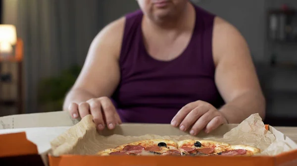 Elhízott ember nézi a zsíros pizza asztal, junk élelmiszer-függőség, a overeating — Stock Fotó