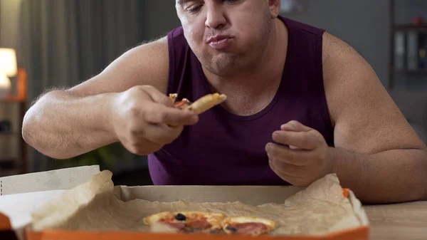 Sovrappeso maschio mangiare pizza con gioia di notte, dipendenza da cibo malsano — Foto Stock