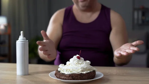 Постійний чоловік дивиться на шоколадний торт зі збитими вершками, нездоровою їжею — стокове фото