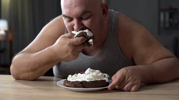 Rommelig zwaarlijvige man gretig eten taart met slagroom, verslaving aan snoep — Stockfoto