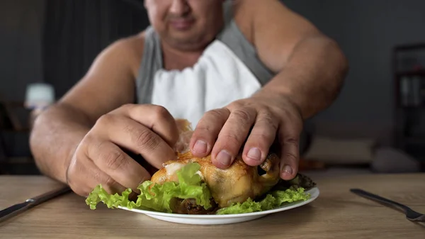 Mau educado homem rasgando frango frito gorduroso com dedos, vício em alimentos gordurosos — Fotografia de Stock