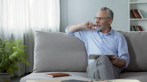 Erwachsener sitzt auf Couch und bucht Hotelzimmer für Urlaub auf Tablet — Stockfoto