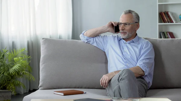 Cuidado padre jubilado sentado en el sofá y llamando a sus hijos, la comunicación —  Fotos de Stock