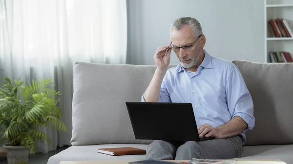 Man in zijn 50s bezig met laptop thuis, beroep en freelance, gadget — Stockfoto