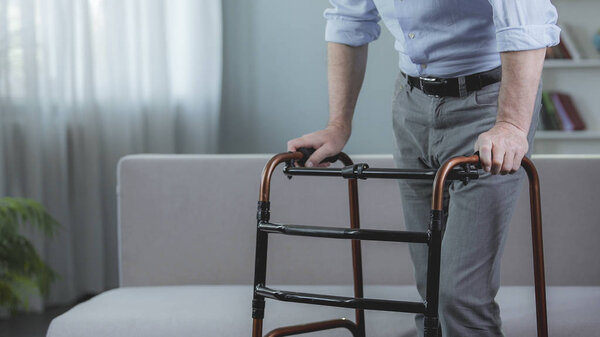 Инвалид пытается двигаться с ходьбой рамкой в больнице, реабилитация
