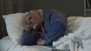 Gri saçlı adam yatakta yatan ve uykusuzluk, depresyon ve sağlık