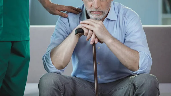 Ondersteunen van senior man, gepensioneerde m/v zittend op de Bank bij verpleeghuis verpleger — Stockfoto