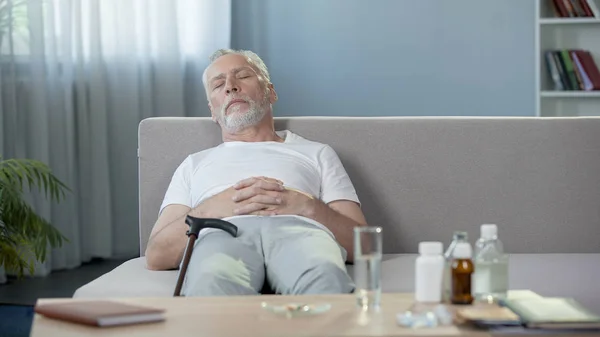 Sénior do sexo masculino dormindo no sofá em casa, relaxar depois de tomar pílulas, medicação — Fotografia de Stock
