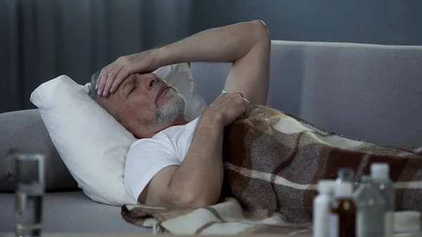Kranker älterer Mann liegt im Bett und leidet unter schrecklichen Kopfschmerzen, Krankheit — Stockfoto