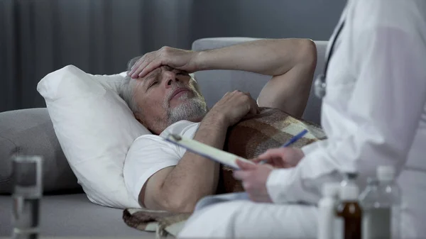 Пенсіонер лежить у ліжку і розмовляє з терапевтом про хвороби, охорону здоров'я — стокове фото