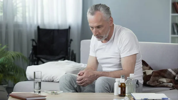 Депресивний старший чоловік сидить на дивані в будинку престарілих, самотності і меланхолії — стокове фото
