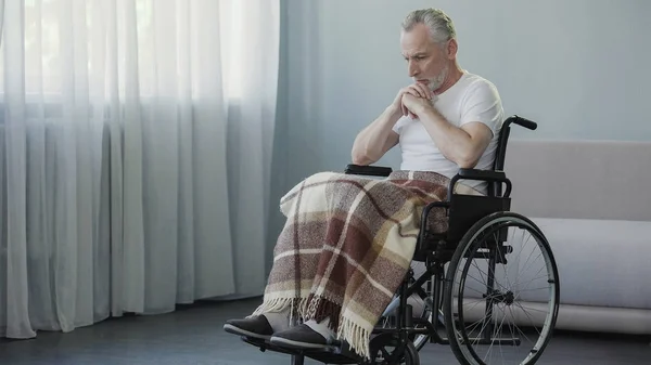 Людина з інвалідністю сидить на інвалідному візку і думає про життя, депресію — стокове фото