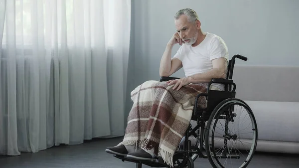 Pensionista triste sentado em cadeira de rodas e esperando por sua família em casa de repouso — Fotografia de Stock