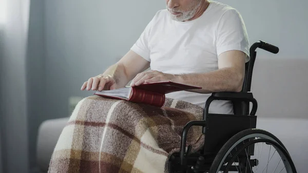 Homem paralisado revisando álbum com fotos, perdendo seu apoio familiar — Fotografia de Stock