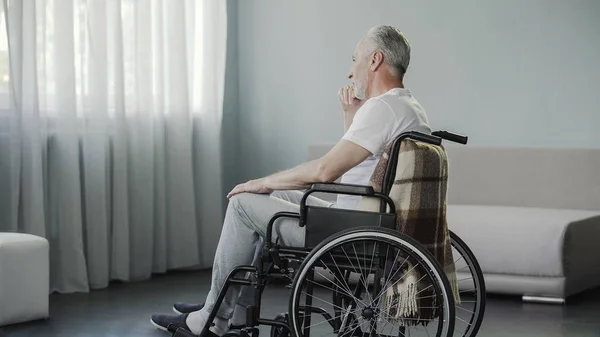 Самотній чоловік у свої 60 років сидить у інвалідному кріслі в реабілітаційному центрі — стокове фото