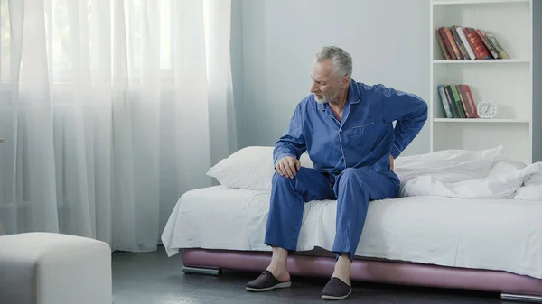 Senior Mann leidet unter starken Rückenschmerzen, Kranker steht morgens aus dem Bett auf — Stockfoto