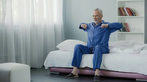 Fröhlicher Senior beim Morgengymnastik im Bett, gute Laune, optimistisch — Stockfoto