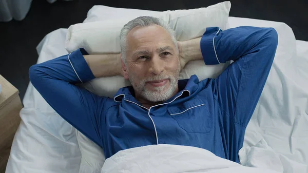 Чоловік в ліжку радіє новим ортопедичним матрацом, комфортний сон — стокове фото