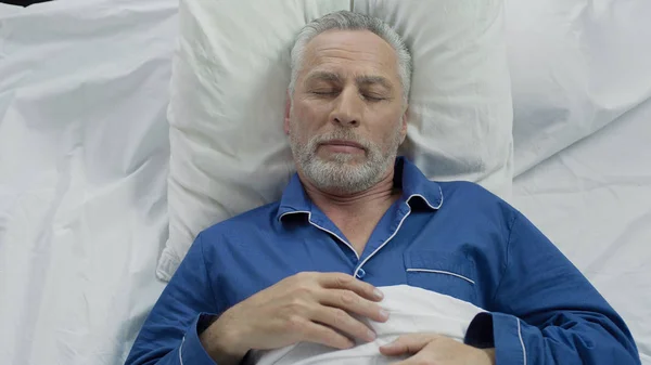 Alter Mann genießt Schlafkomfort dank orthopädischer Matratzen und Kissen — Stockfoto