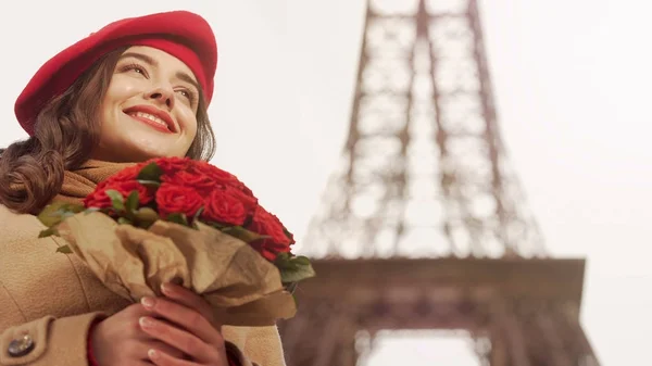 Gelukkig mooi meisje bewonderen boeket van rode rozen op achtergrond van Eiffel Tower — Stockfoto