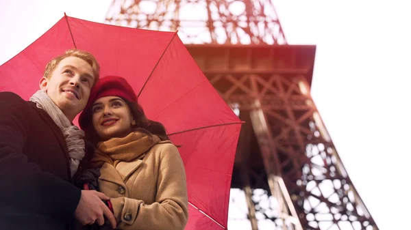 Feliz casal apaixonado de pé sob guarda-chuva em Paris, tendo férias românticas — Fotografia de Stock