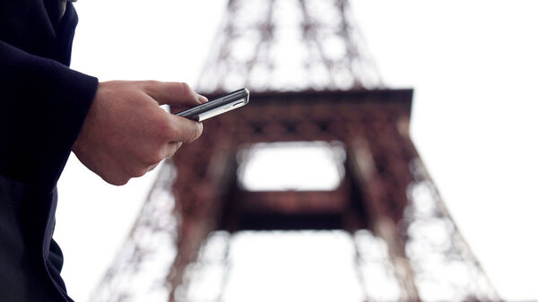 Человек путешествует по интернету на смартфоне, бронирует билеты и отель для командировки
