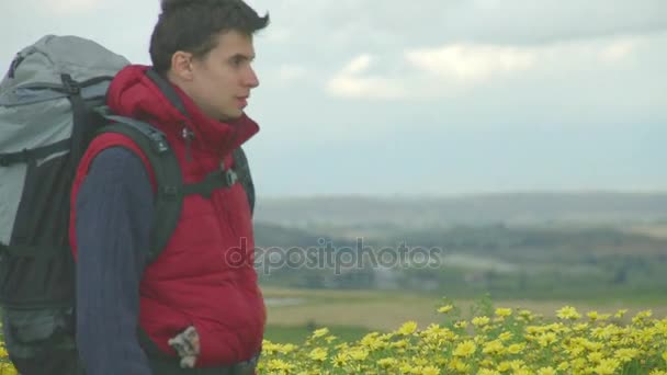 Joven con traje de camping y mochila mirando montañas, viajando — Vídeos de Stock