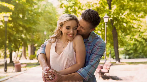Bello fidanzato che abbraccia la sua bella ragazza, appuntamento romantico nel parco — Foto Stock