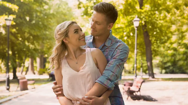 Netter Kerl und Mädchen schauen einander mit Liebe zärtlich an, kuscheln im Park — Stockfoto