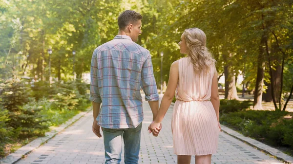 Ζευγάρι στην αγάπη strolling μέσω όμορφη καλοκαιρινή πάρκο, κρατώντας απαλά τα χέρια — Φωτογραφία Αρχείου
