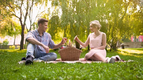 Coppia innamorata cercando quello che hanno per il picnic nel cestino, meraviglioso riposo — Foto Stock