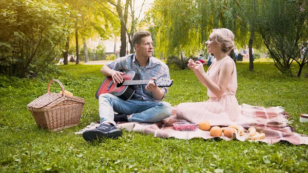 Cuplu având întâlnire romantică, cântând cântece și cântând la chitară, stând în parc — Fotografie, imagine de stoc