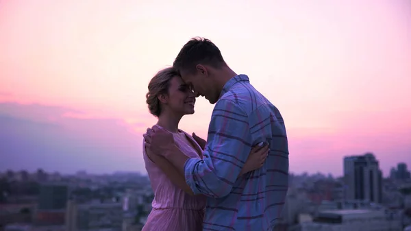 Любящий парень обнимает свою прекрасную даму на открытой террасе, романтический городской пейзаж — стоковое фото