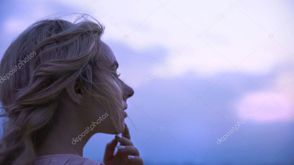 Girl touching her lips, thinking about beloved man, sadly looking into distance