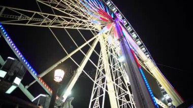 Giant Ferris wheel dönen neşeli gece eğlence parkı, renkli ışıklı